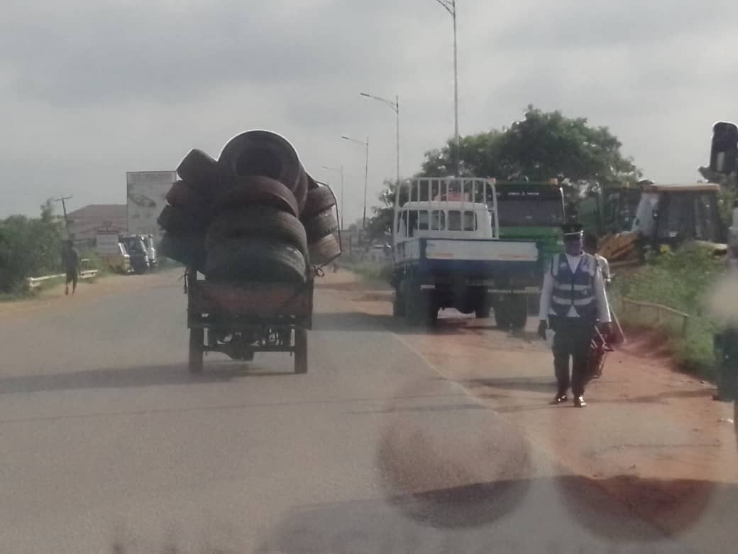 In the picture is an MTTD personnel, right, ignoring the overloaded rickety tricycle on the Dawhenya road